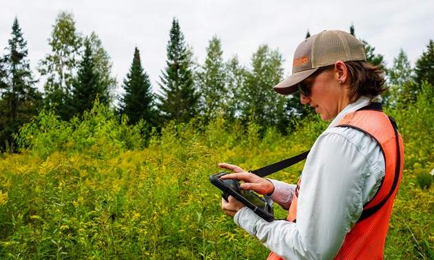 VELCO employee making notes on a device in a field
